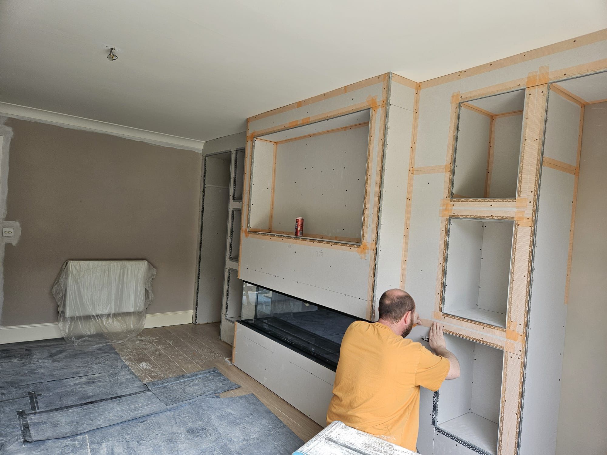 Plasterer taping the recesses of a boarded media wall