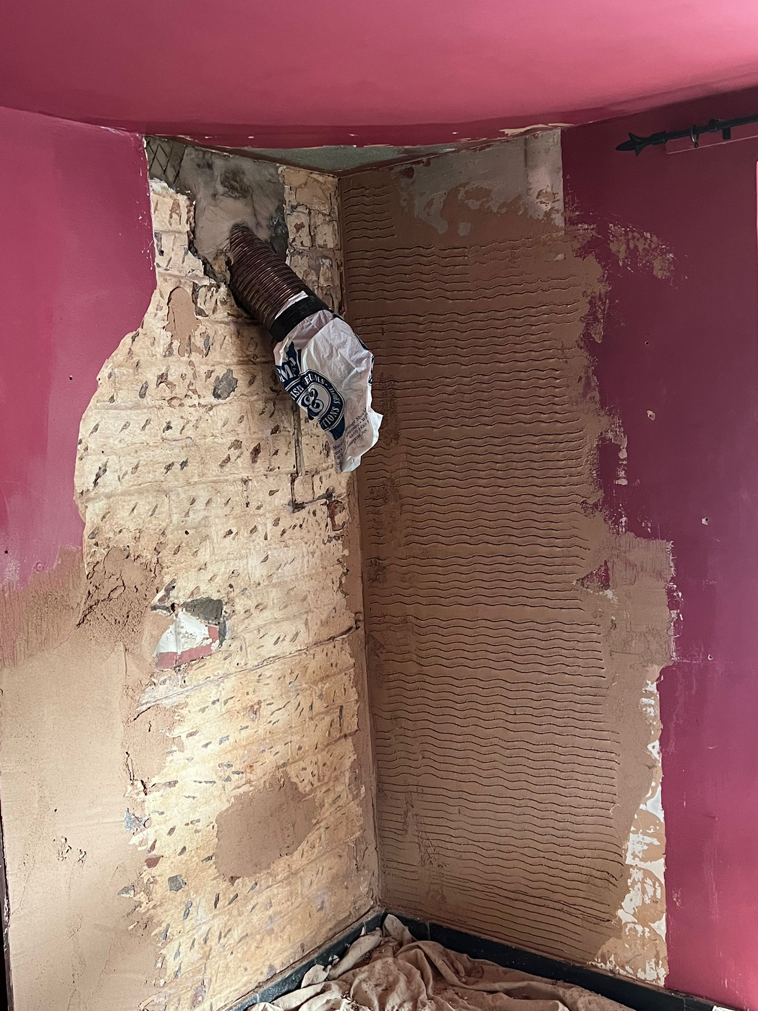 Scratch coat applied over exposed brickwork in alcove
