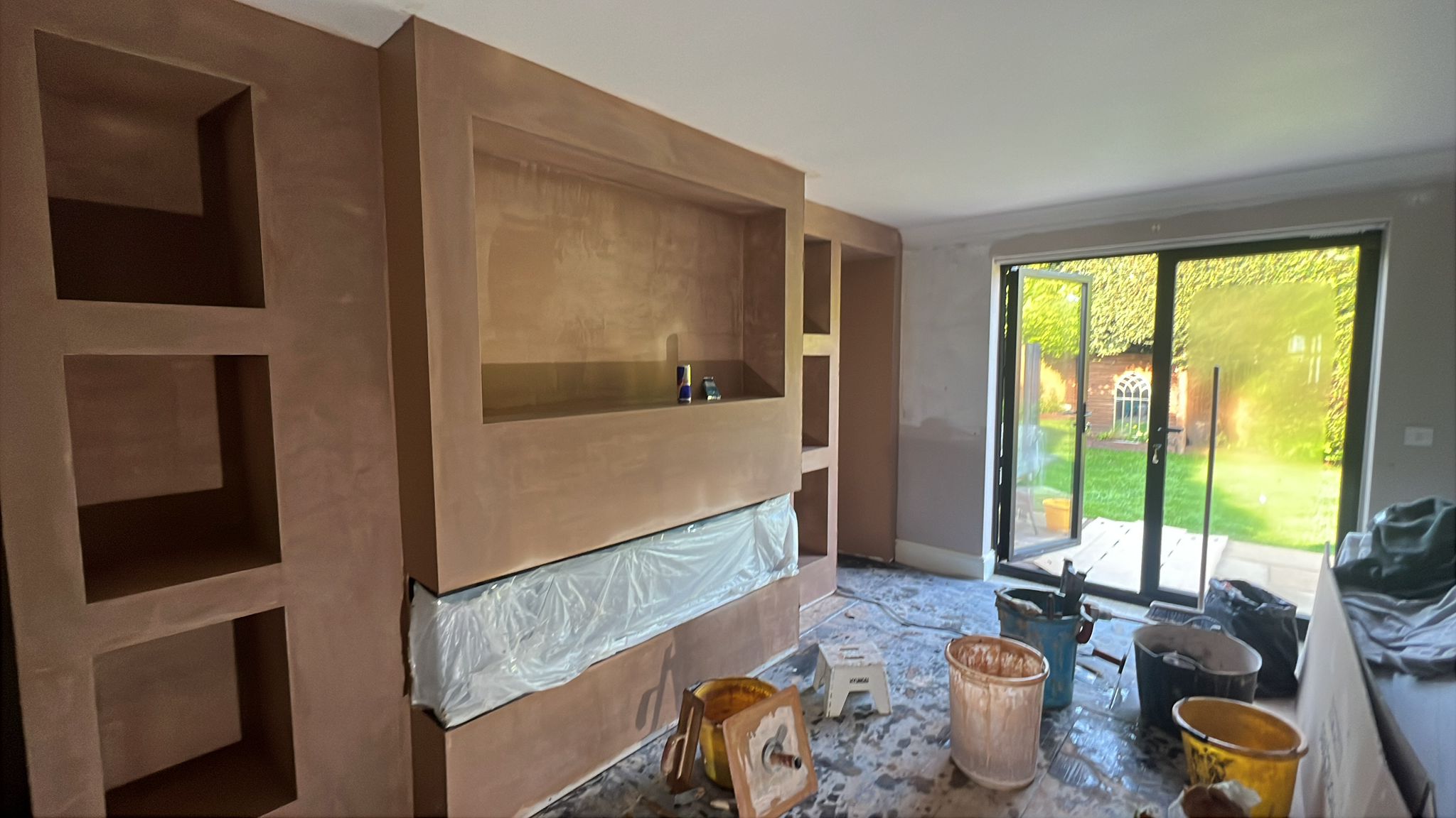 Media wall with fresh wet plaster skim coat to niches and TV recess