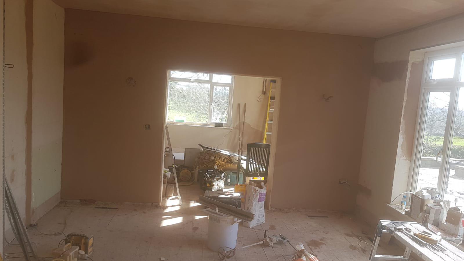 Large open-plan room freshly plastered with doorway through to second room